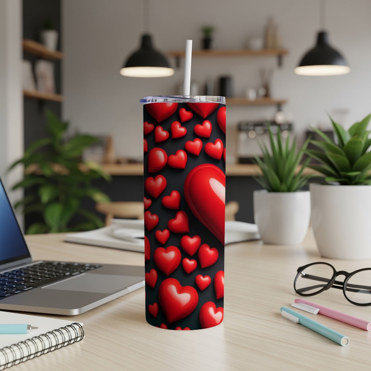 Red hearts pattern on a stainless steel tumbler with straw on a desk.