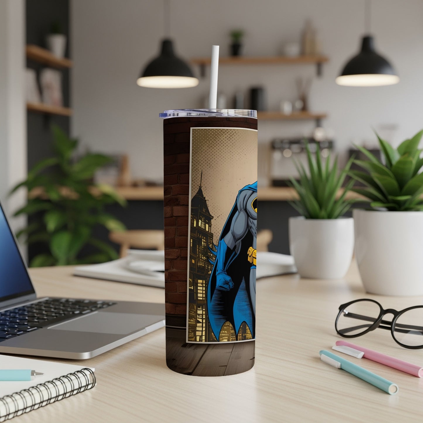 Batman illustration on a white tumbler with a straw, on a desk.