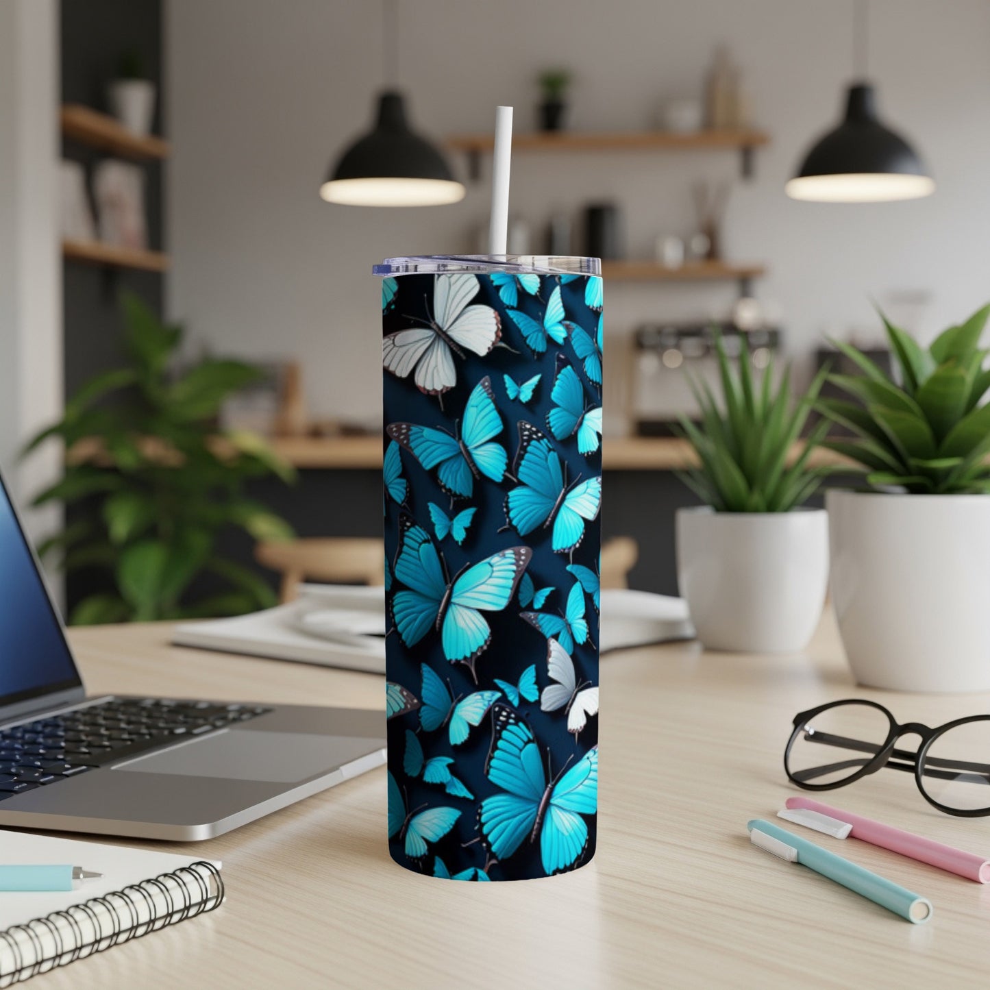 Blue and white butterflies adorn a stainless steel tumbler on a desk.