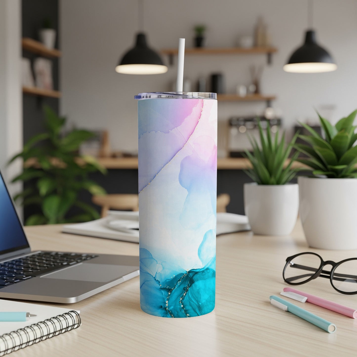 Abstract watercolor and gold design on a tall, slim tumbler with a straw.