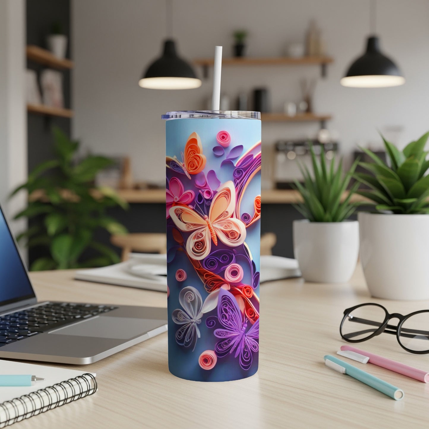Tumbler with colorful quilled butterflies and floral accents on a desk.