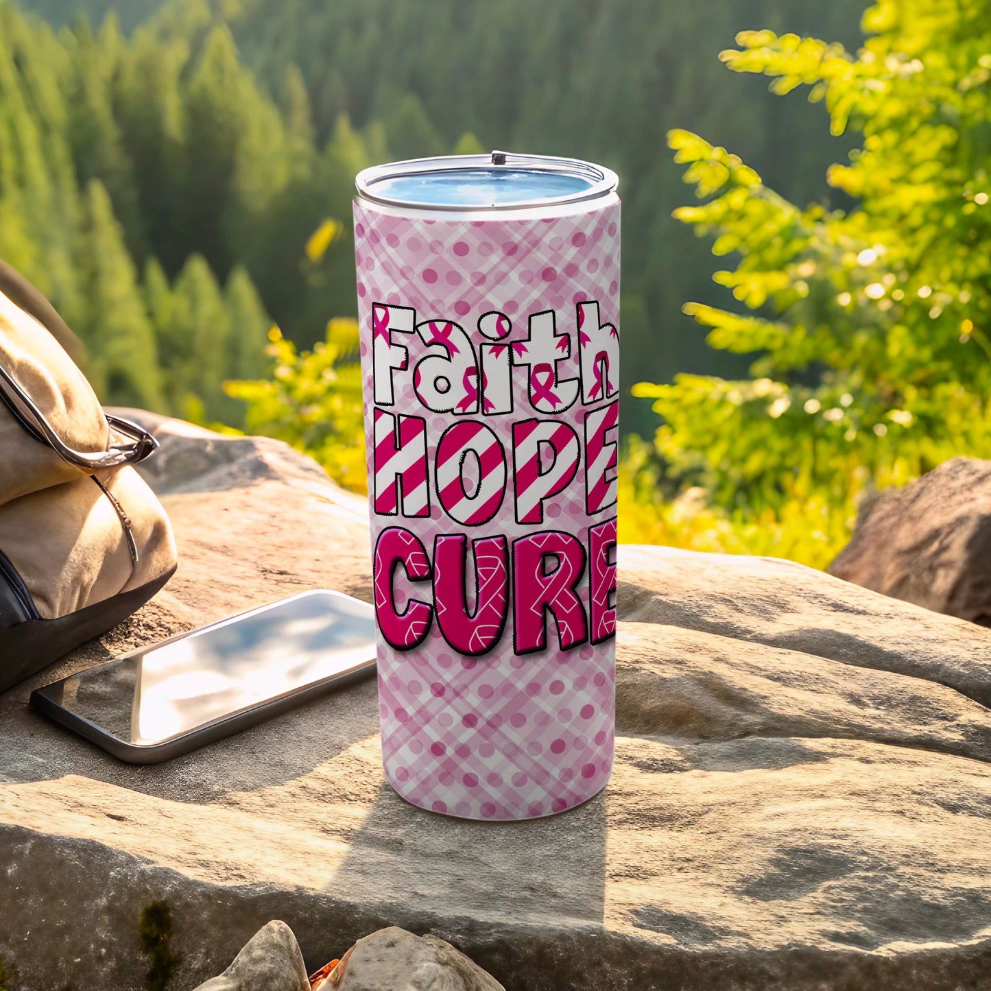 Pink tumbler with "Faith Hope Cure" text and ribbon pattern on rocks.
