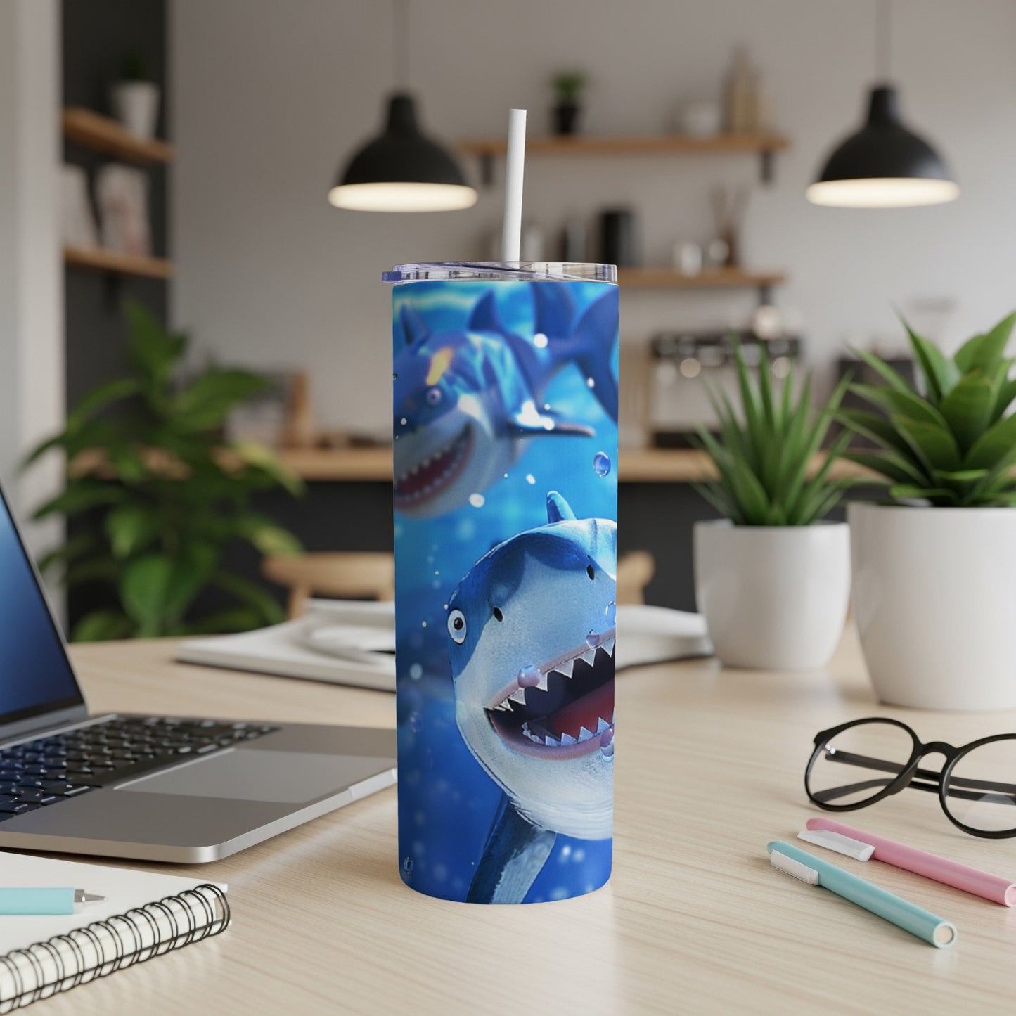 Cartoon sharks on a blue background printed on a tumbler with a white straw.