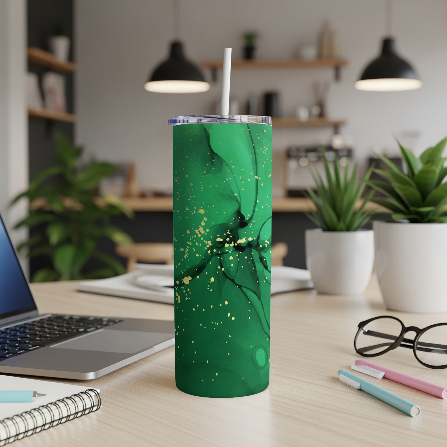 Green and gold marbled tumbler with white straw on a desk.