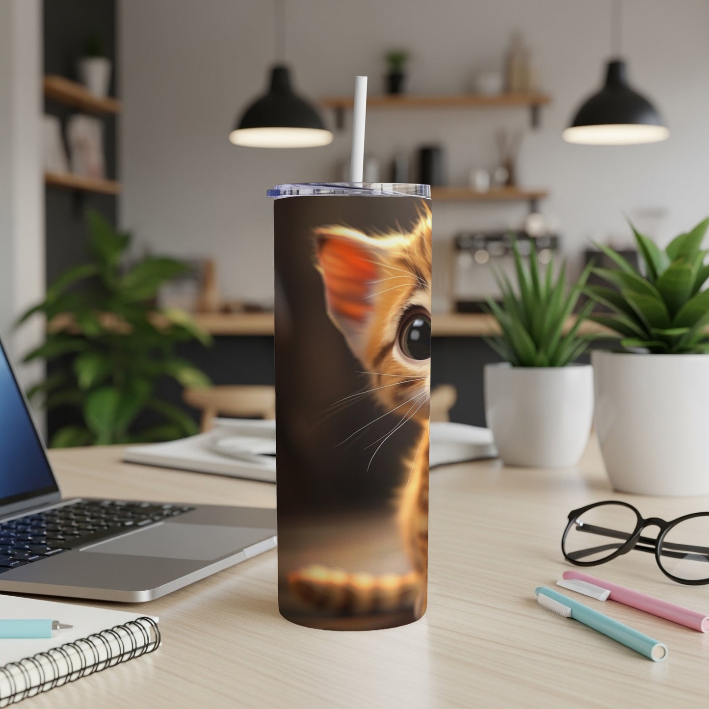Close-up of a kitten's face on a skinny tumbler with a straw.