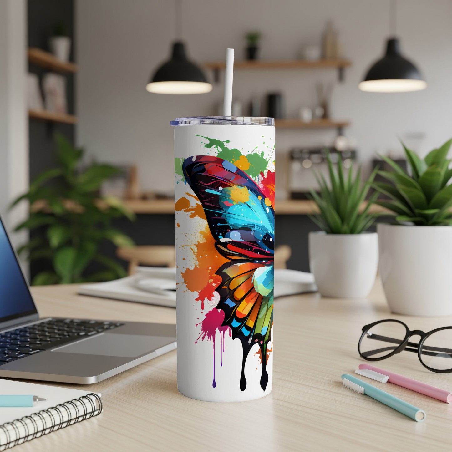 White tumbler with colorful butterfly wing design, on a desk.
