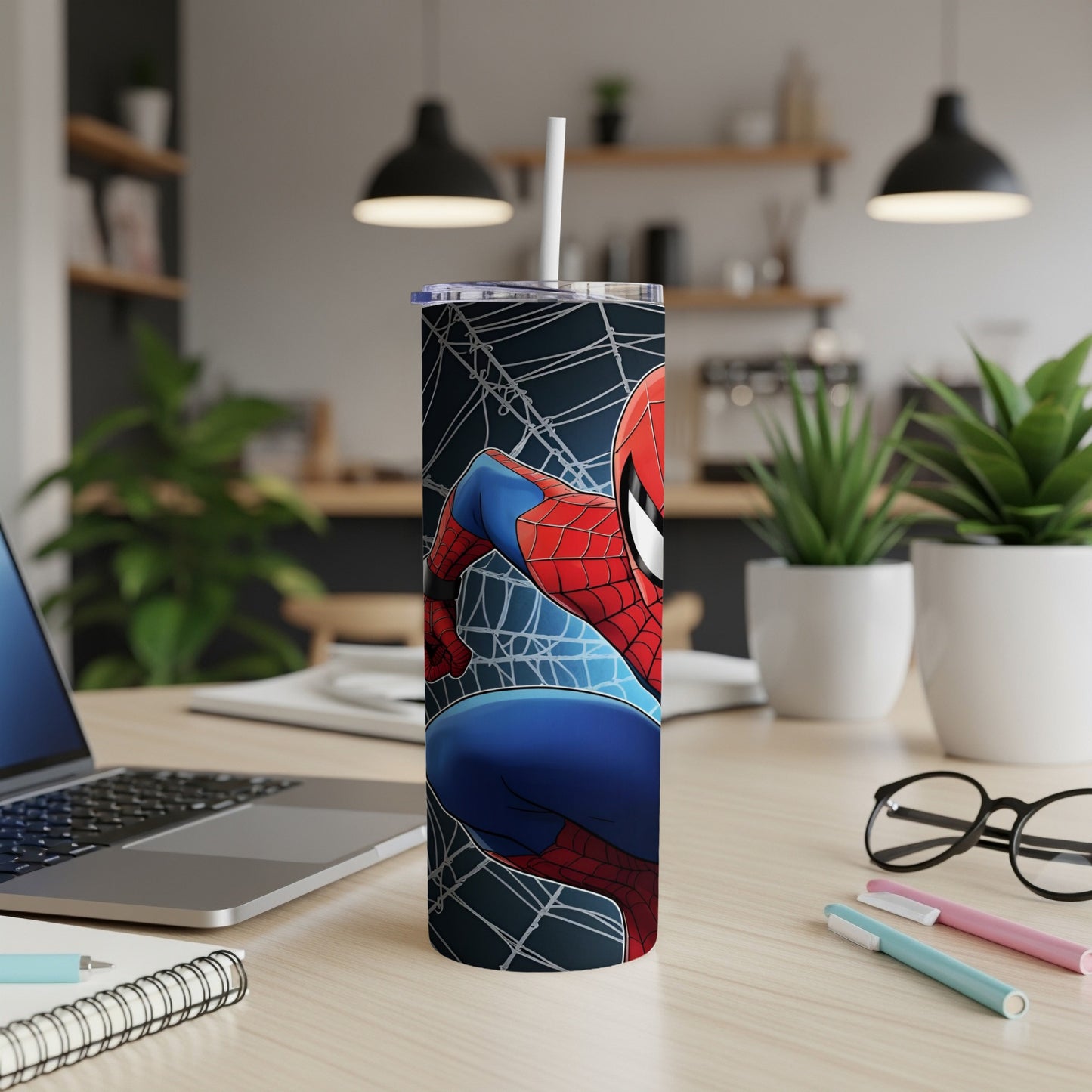 Spider-Man on a white tumbler with a straw, on a wooden desk.