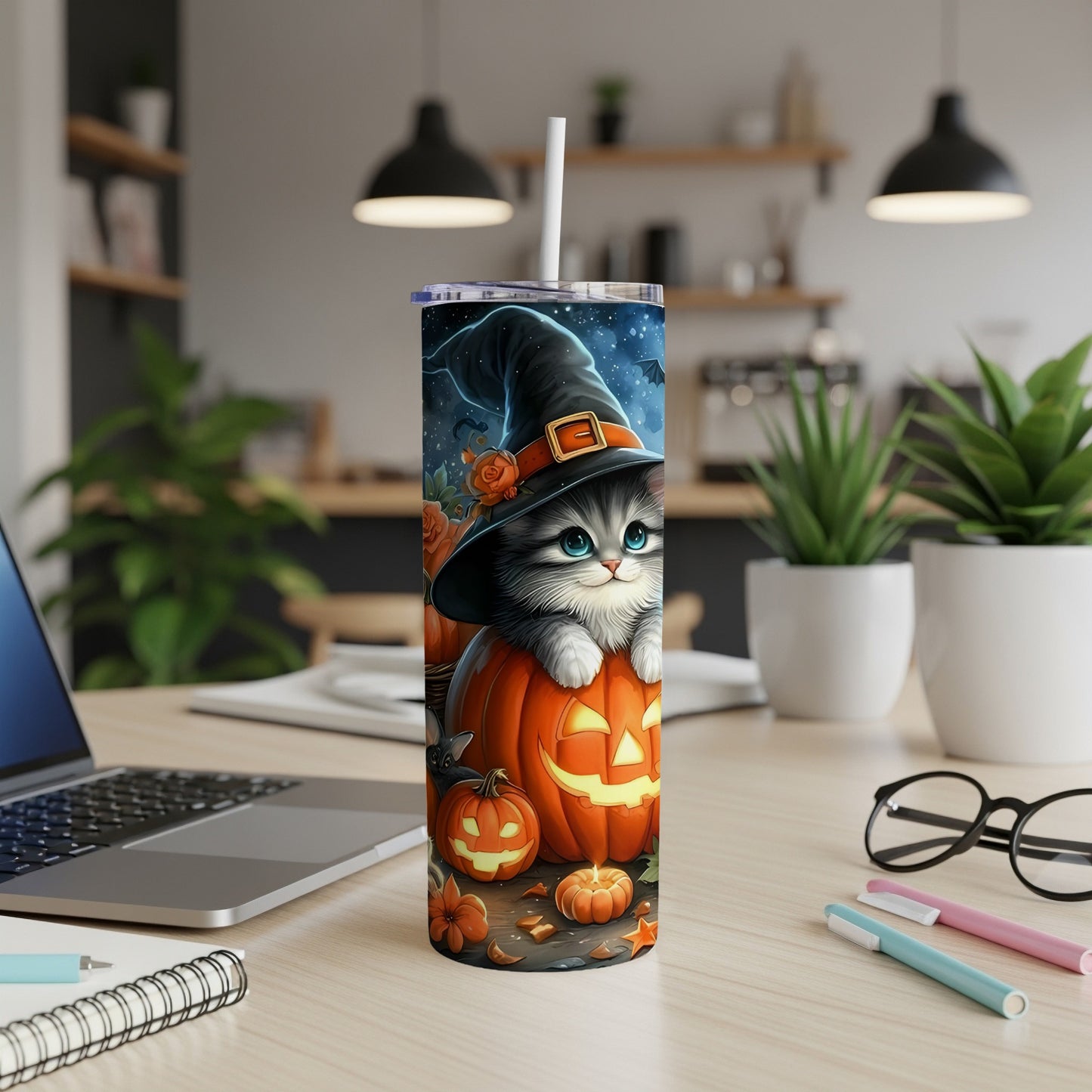 Tumbler featuring a cartoon cat in a witch hat and pumpkins on a desk.