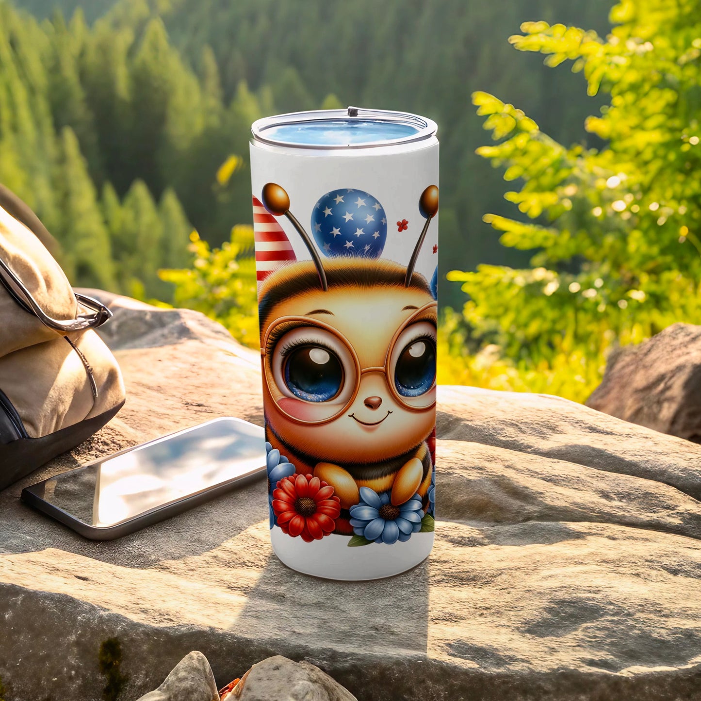 Tumbler with cartoon bee wearing glasses and holding balloons, set on rocks.