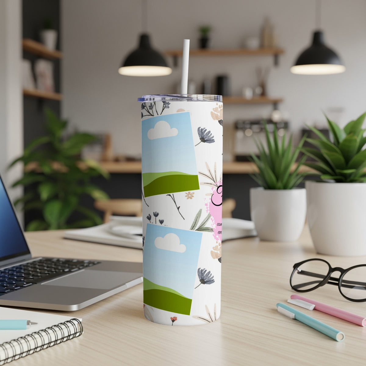 White tumbler with floral pattern and photo frames on a desk.