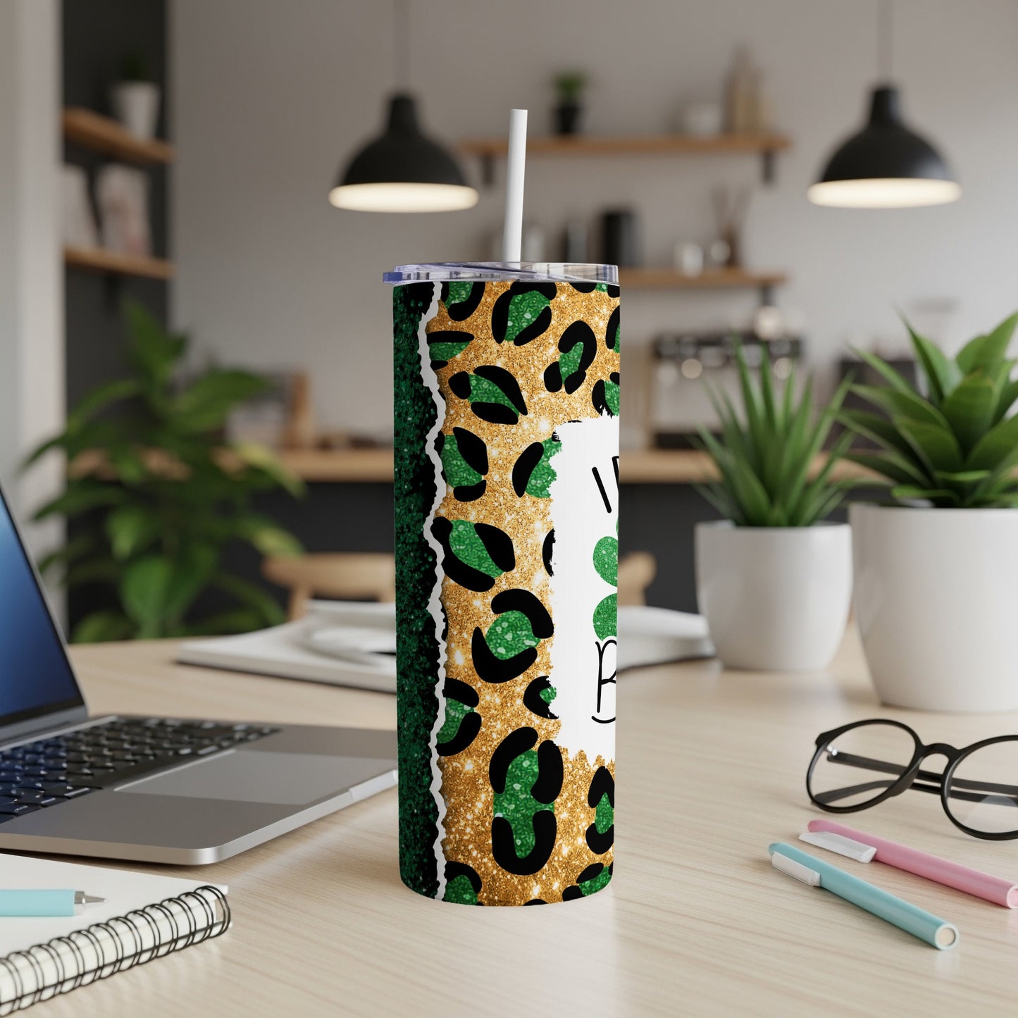 Green leopard print tumbler with glitter, straw, and text on a desk.