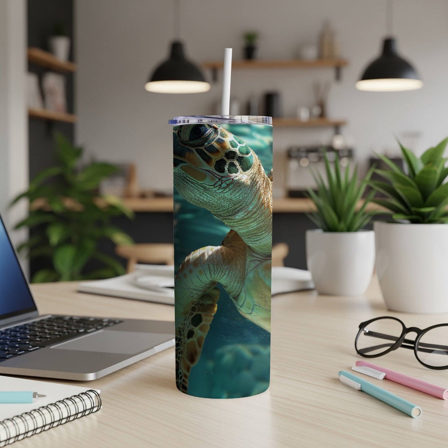 Sea turtle design on a white tumbler with a straw, on a desk.
