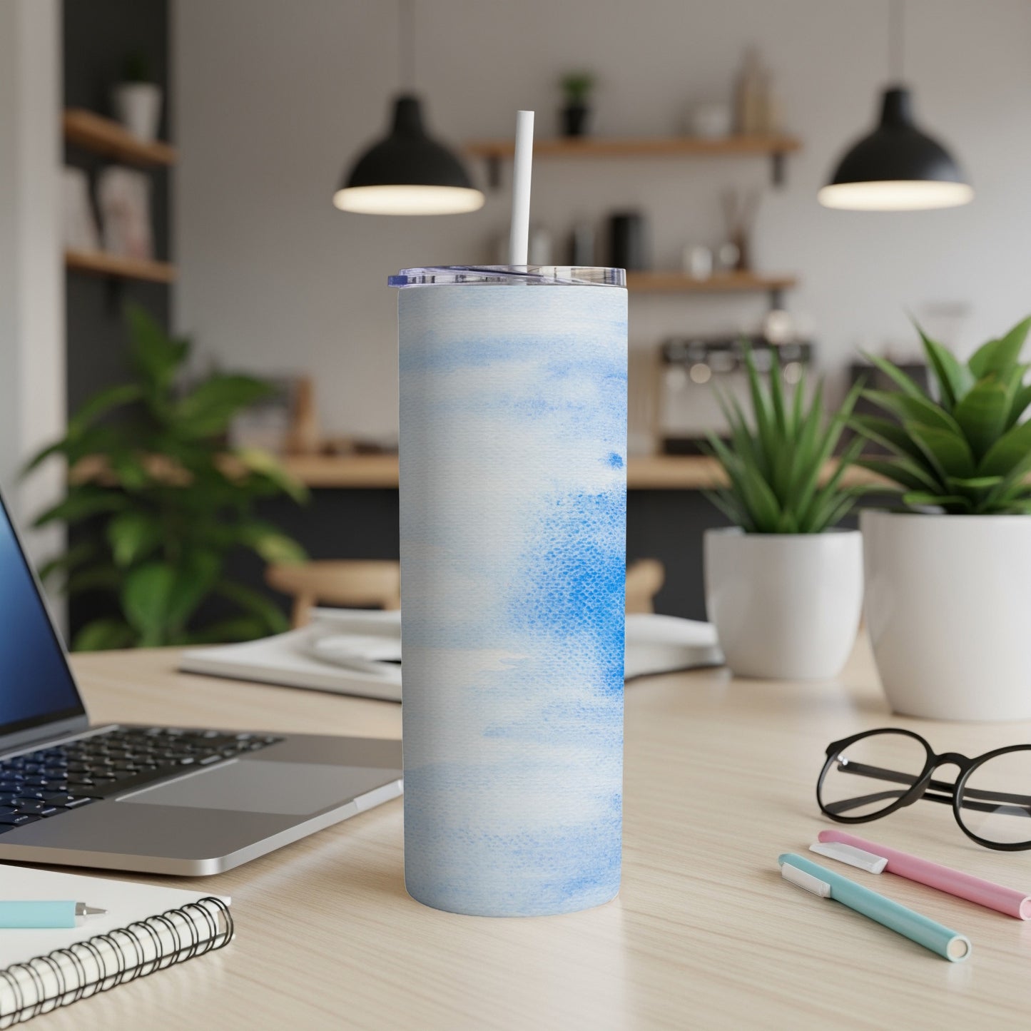 White and blue watercolor pattern tumbler with straw on desk.