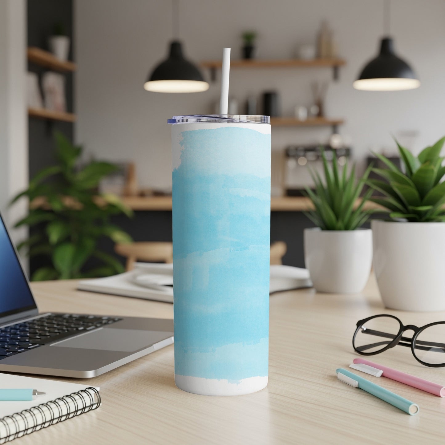 Blue watercolor pattern skinny tumbler with straw on a desk.