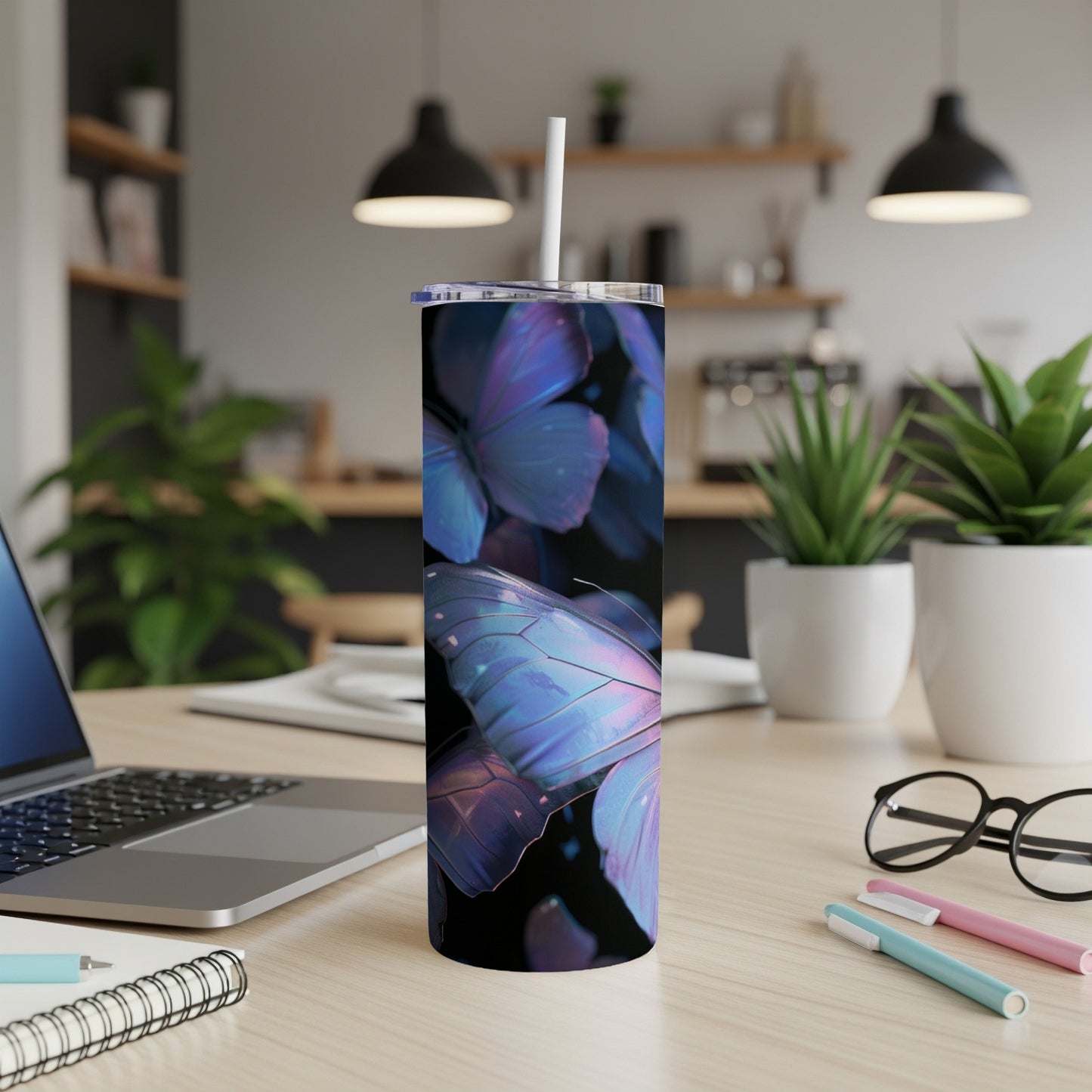 Tall tumbler with iridescent butterfly design and white straw on desk.