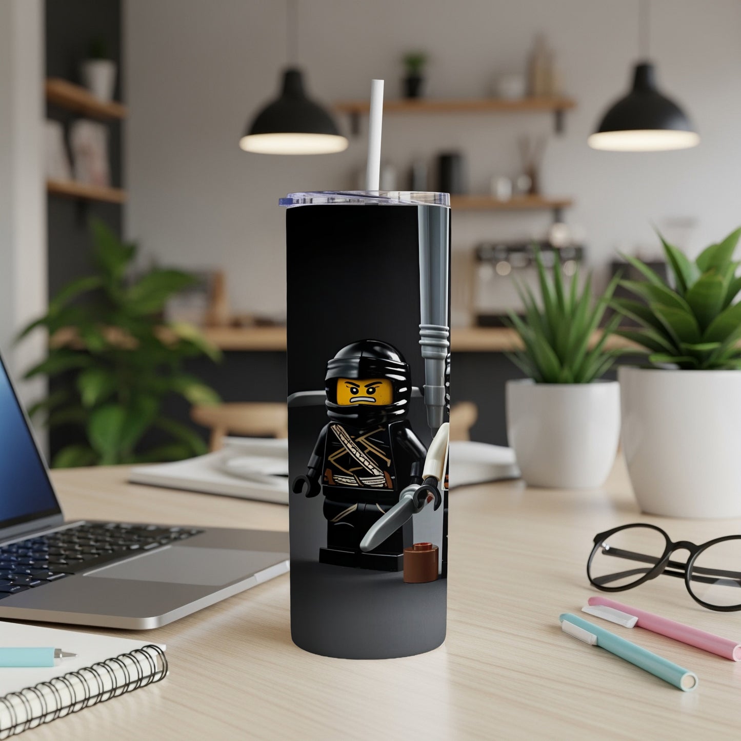 Black LEGO ninja tumbler with straw on a desk.