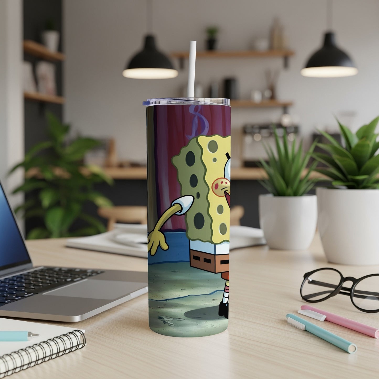SpongeBob SquarePants tumbler with a straw, on a desk with a laptop and pens.