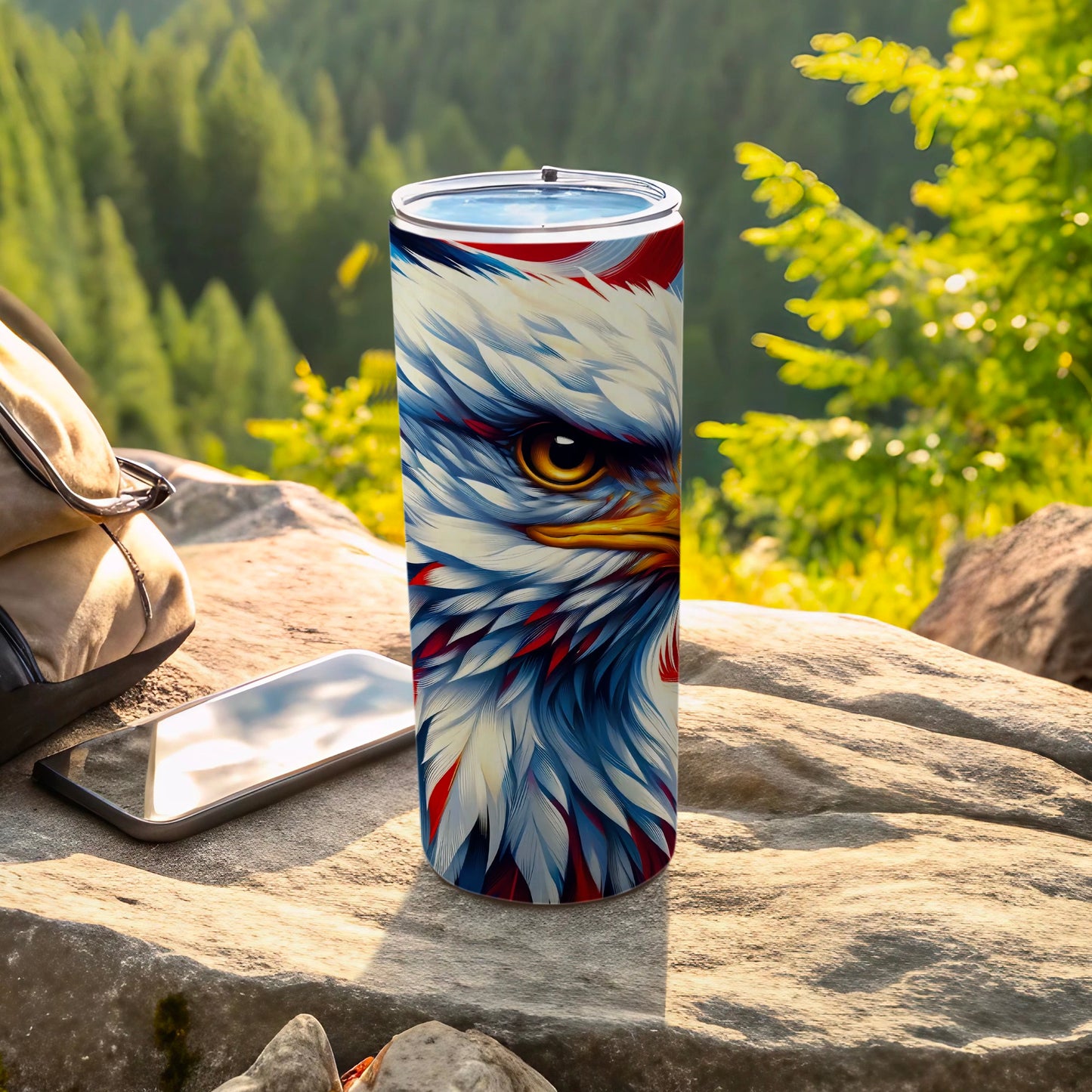 Tumbler with detailed bald eagle design on outdoor rocky surface.