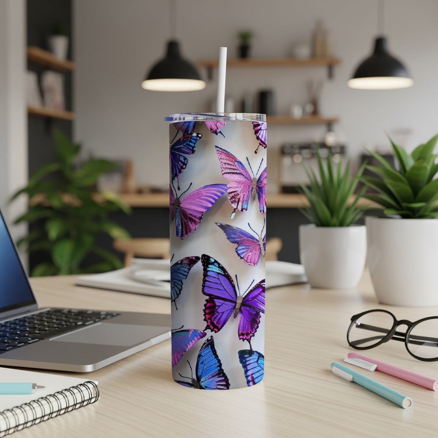 Tall tumbler with colorful purple and blue butterflies on a desk.