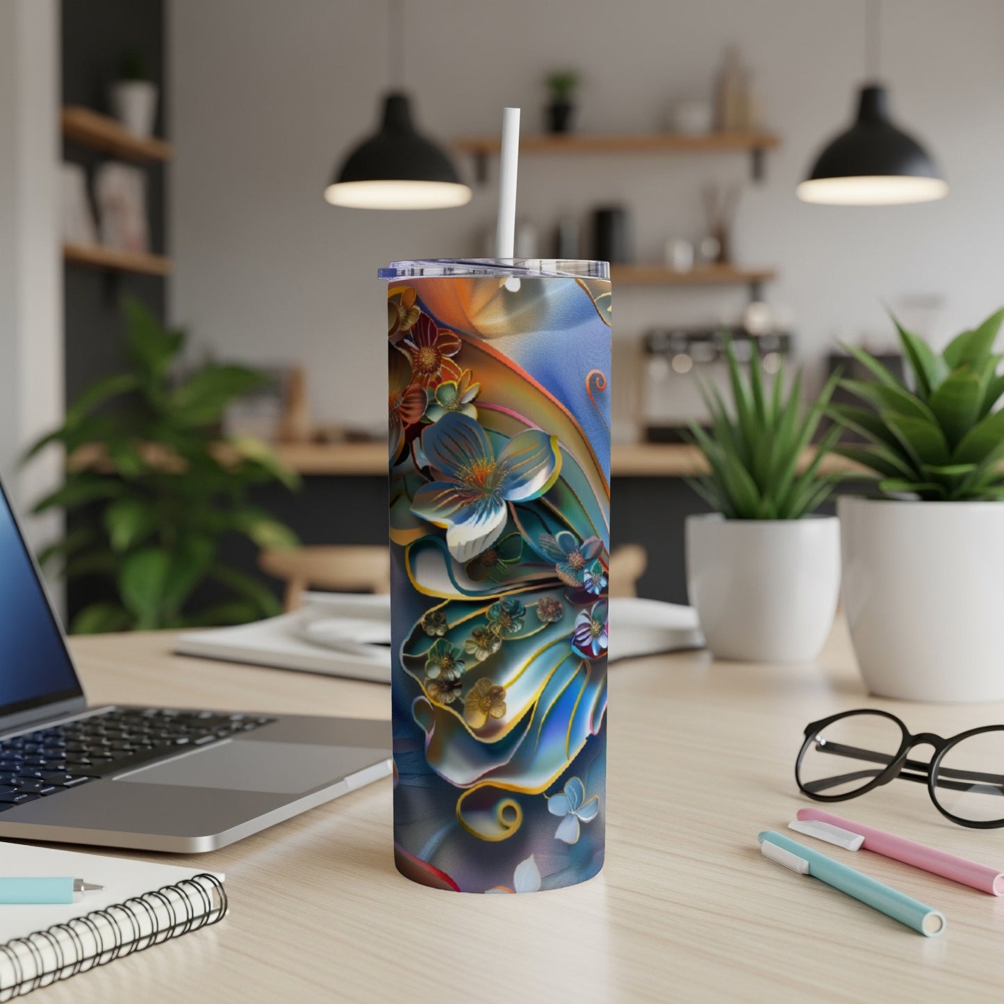 Blue and gold floral tumbler with straw on a desk.