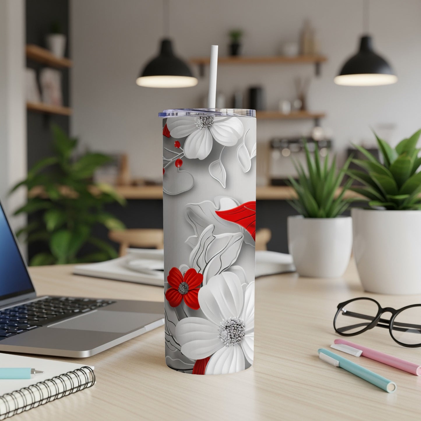 White and red floral tumbler with straw on a desk.