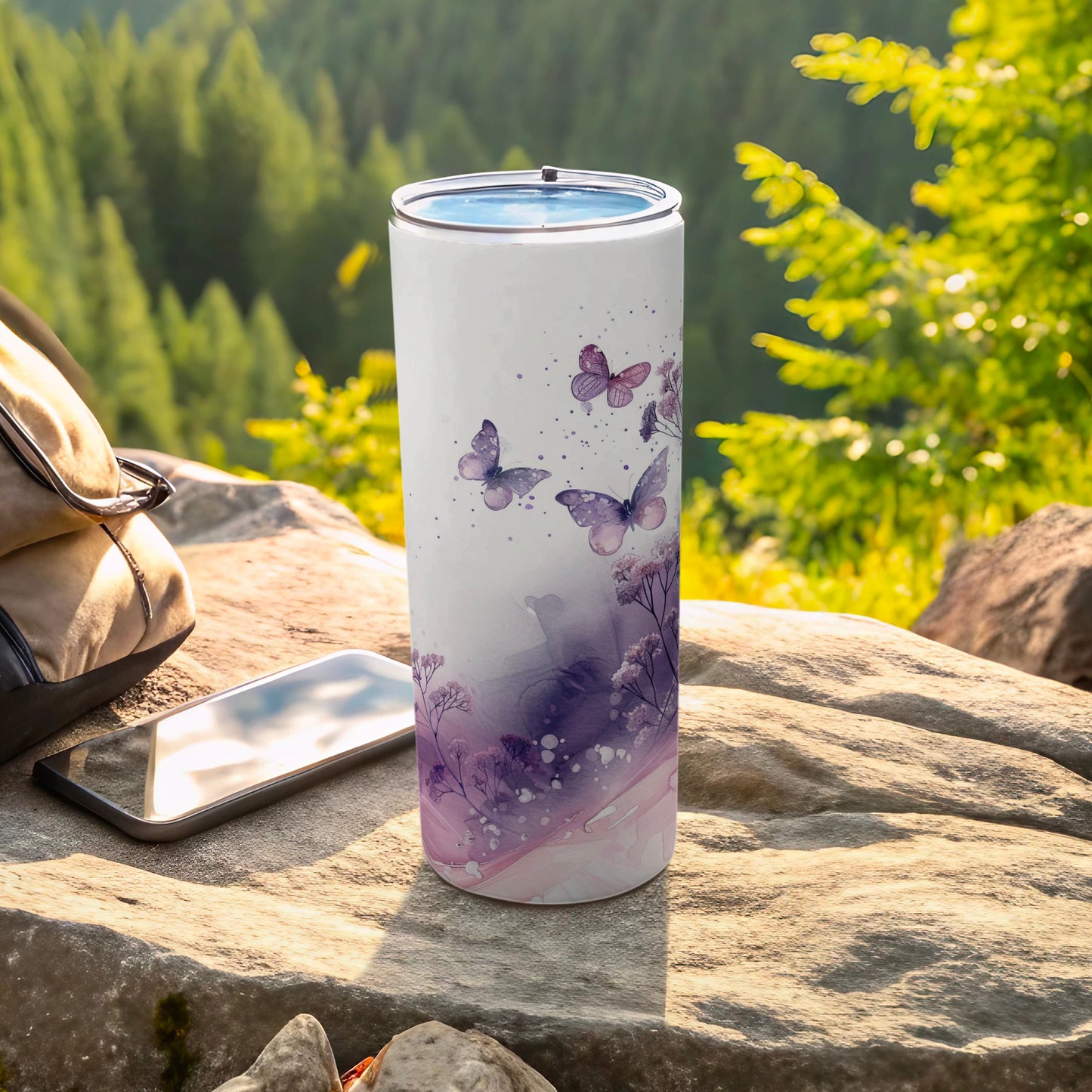 White tumbler with purple watercolor butterflies and flowers, outdoors.