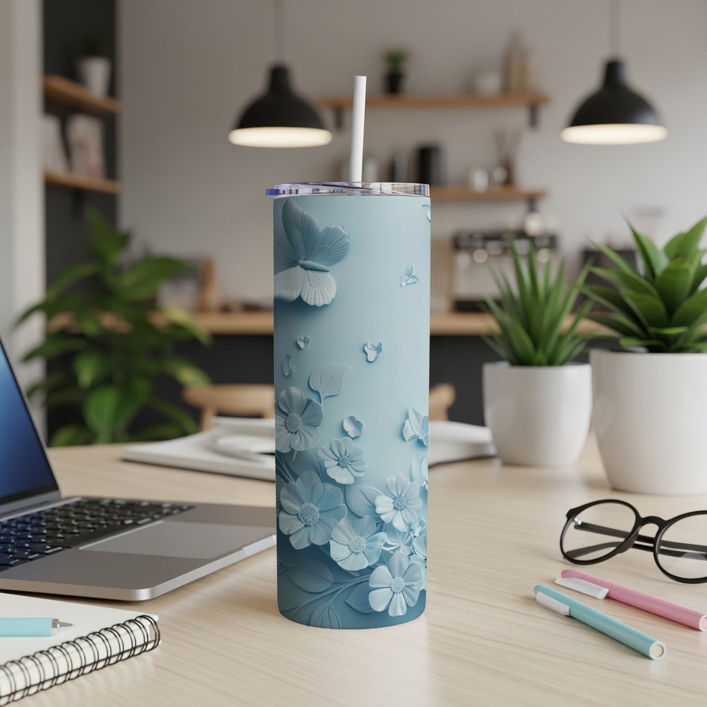 Light blue floral tumbler with butterfly accents on a desk.