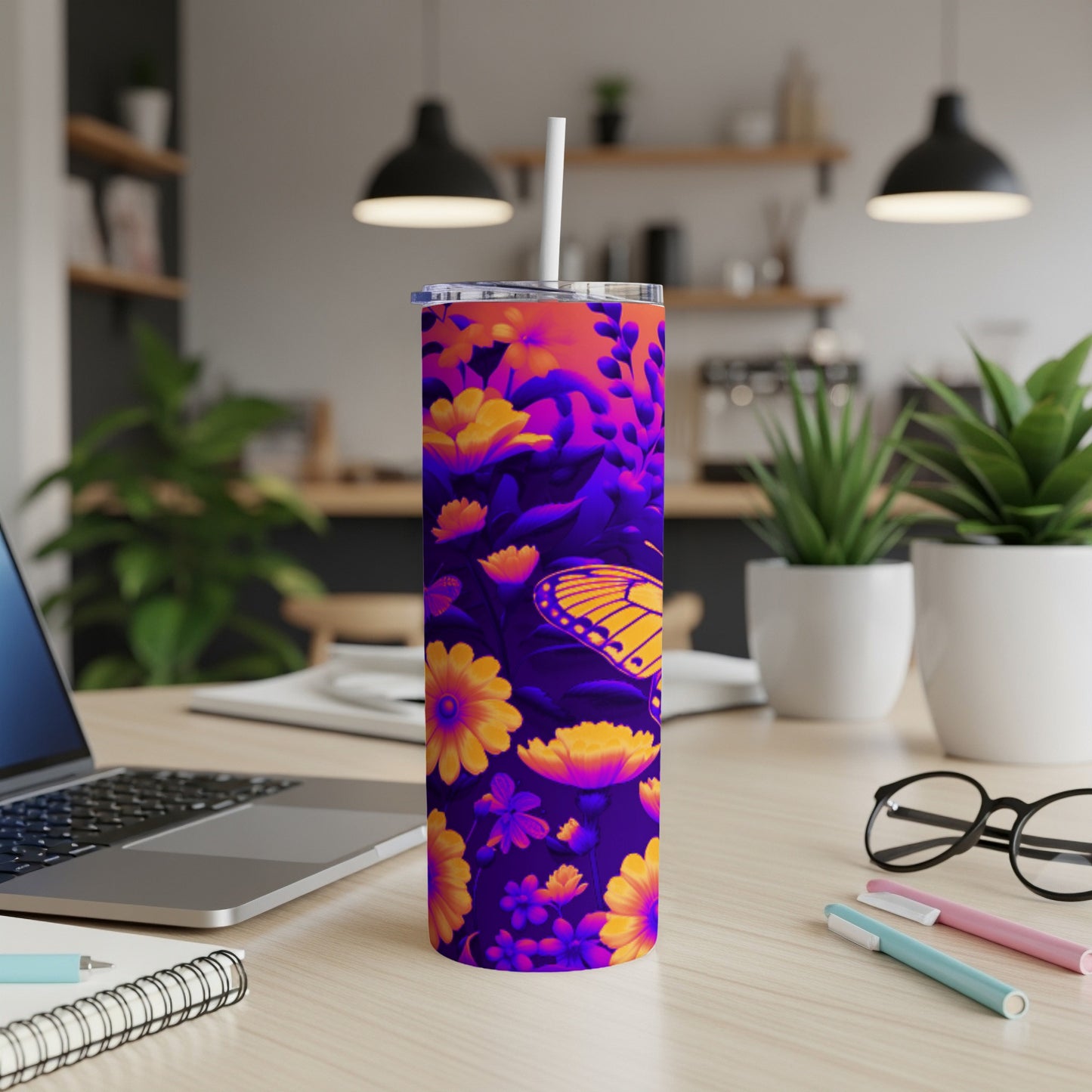 Purple tumbler with yellow flowers and orange butterfly, on a desk.
