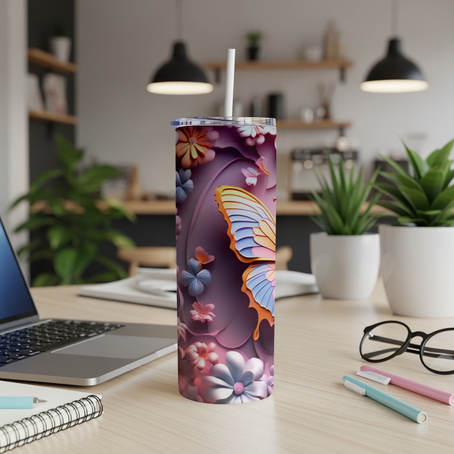 Tumbler with butterfly and floral design on a desk.
