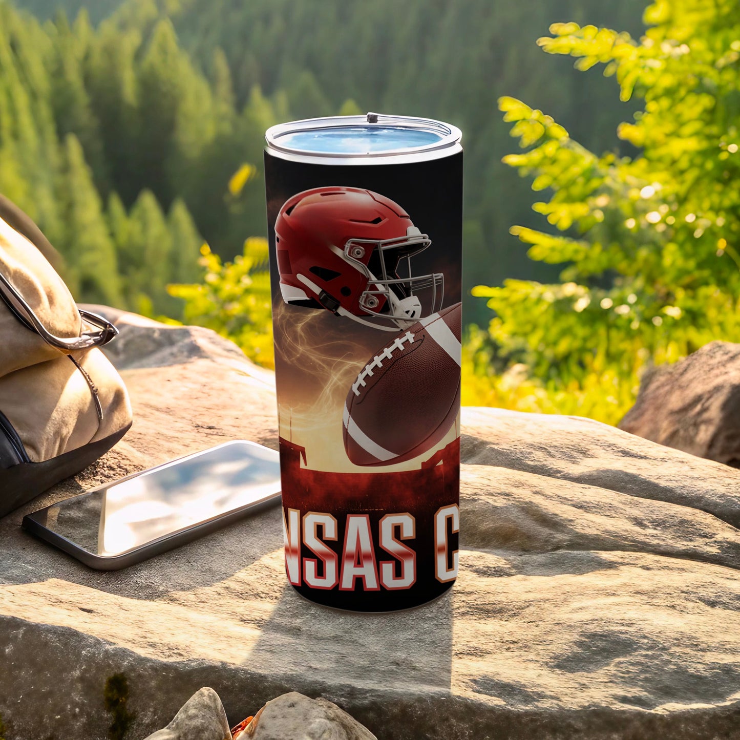Tall tumbler with a football helmet, football, and text "ansas C" on a stone surface.