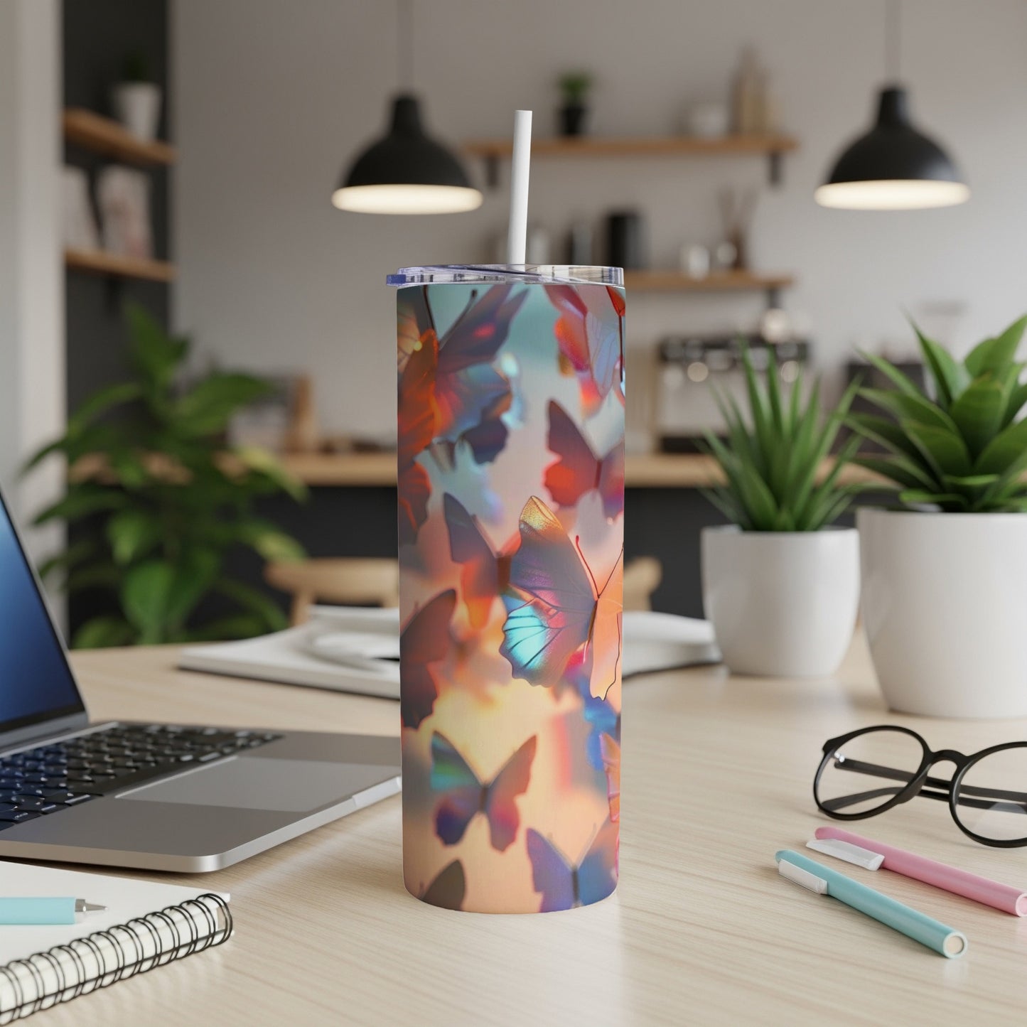 Tumbler with a colorful butterfly print on a desk next to a laptop.