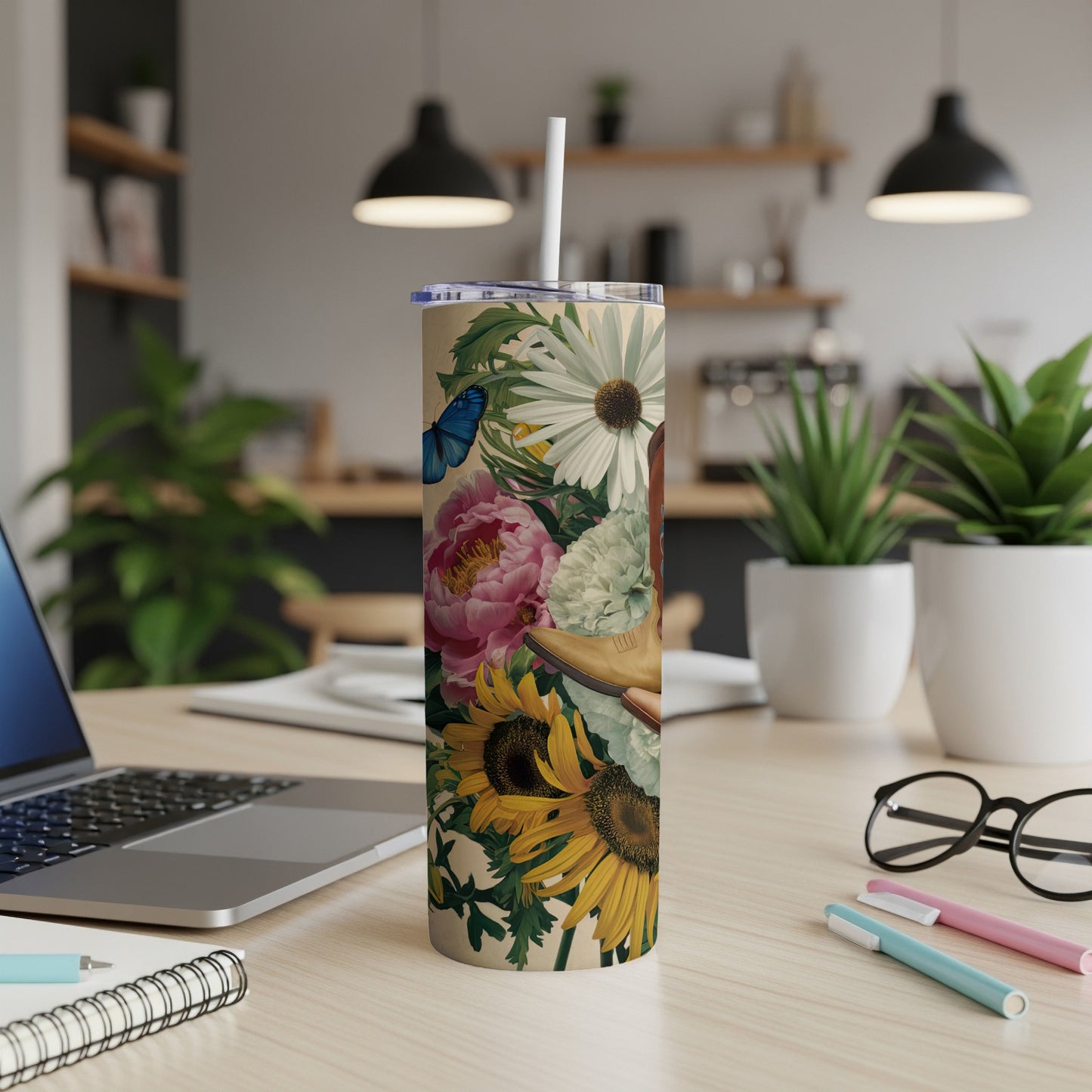Floral and butterfly illustration on a white insulated tumbler with a straw.