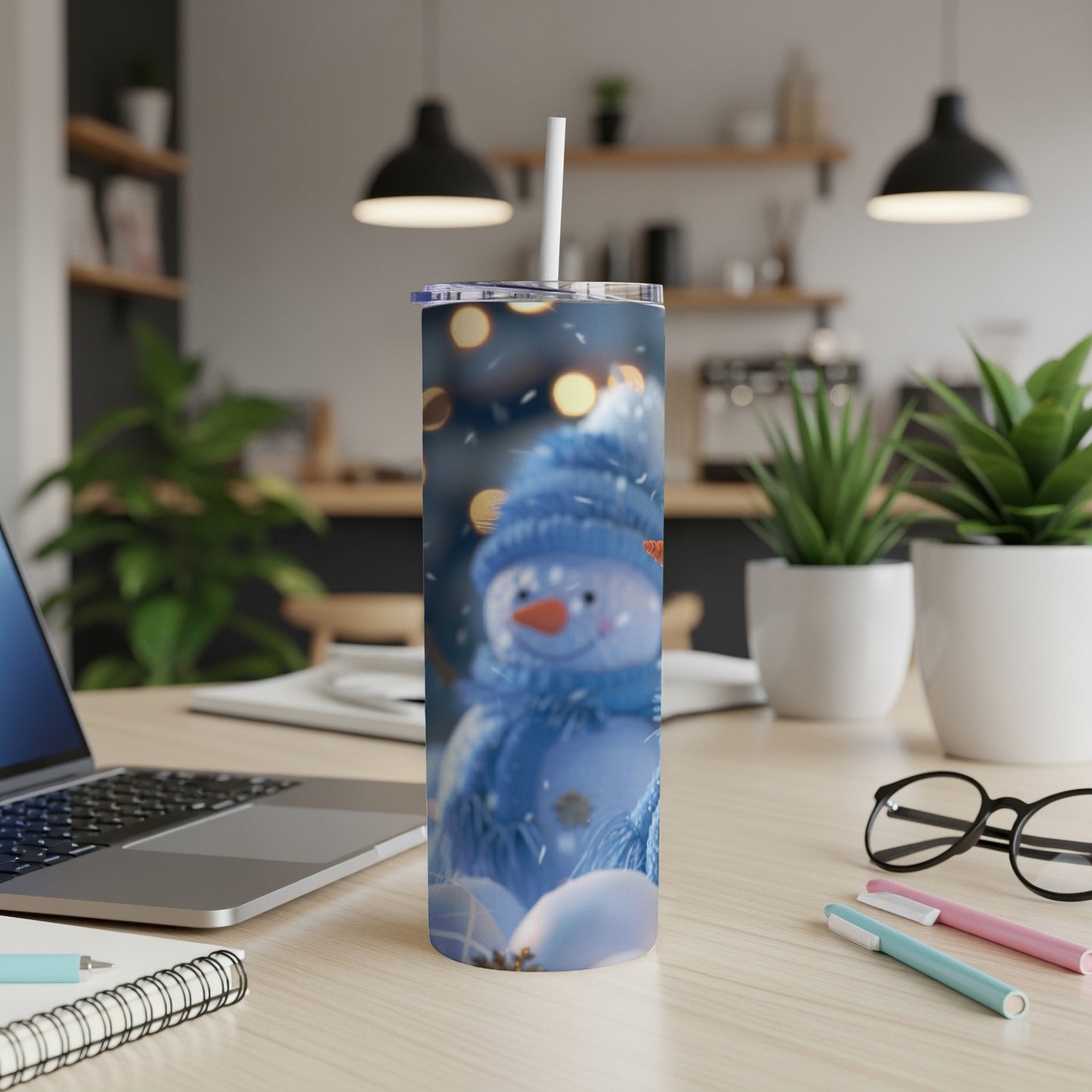 Blue snowman tumbler with white straw in a cozy room setting.