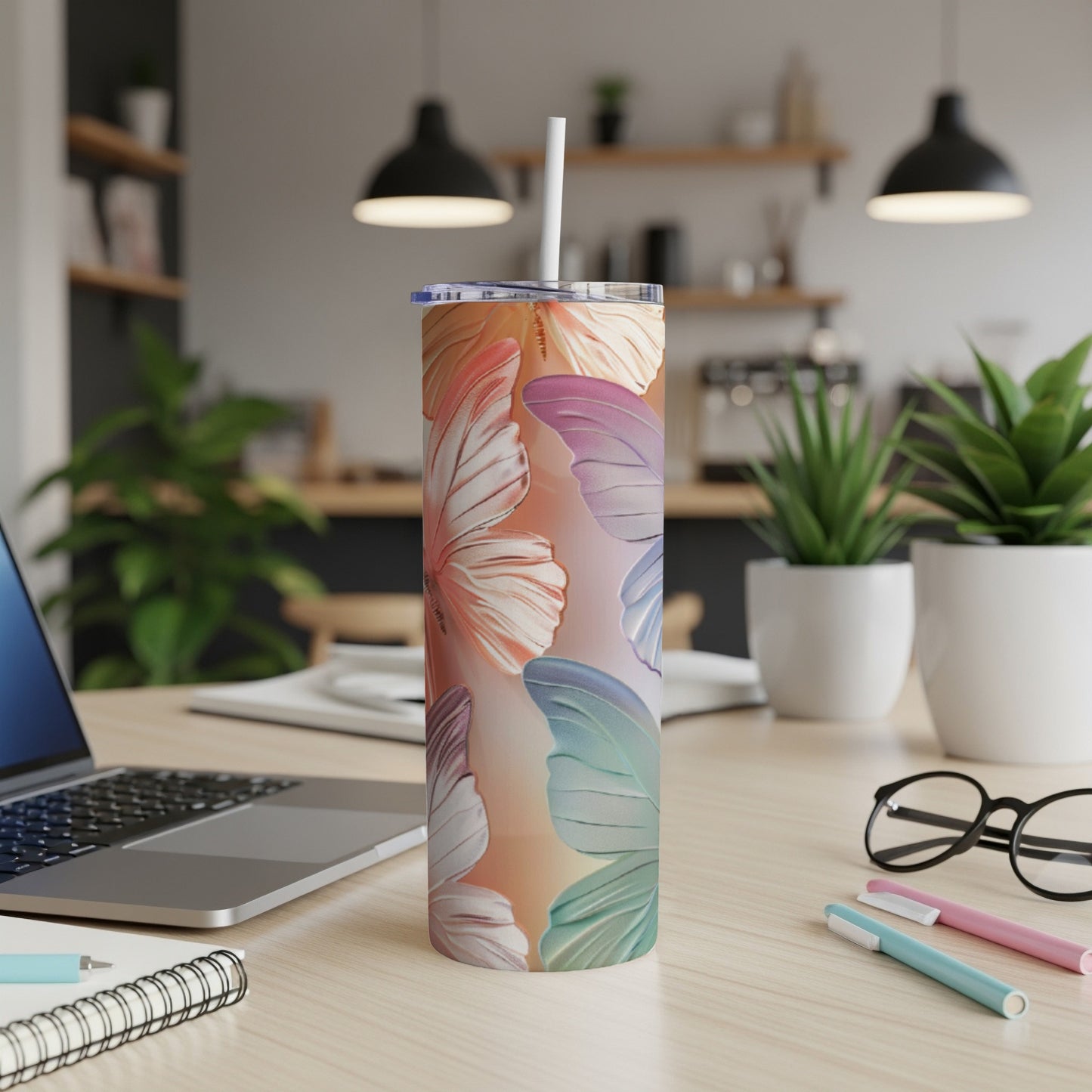 Tumbler with colorful butterfly wing pattern and white straw, on a desk.