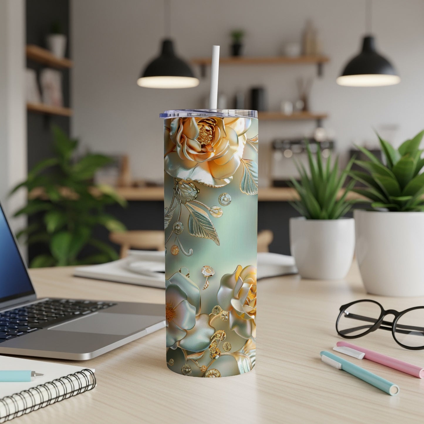 Gold floral tumbler with straw on a desk.