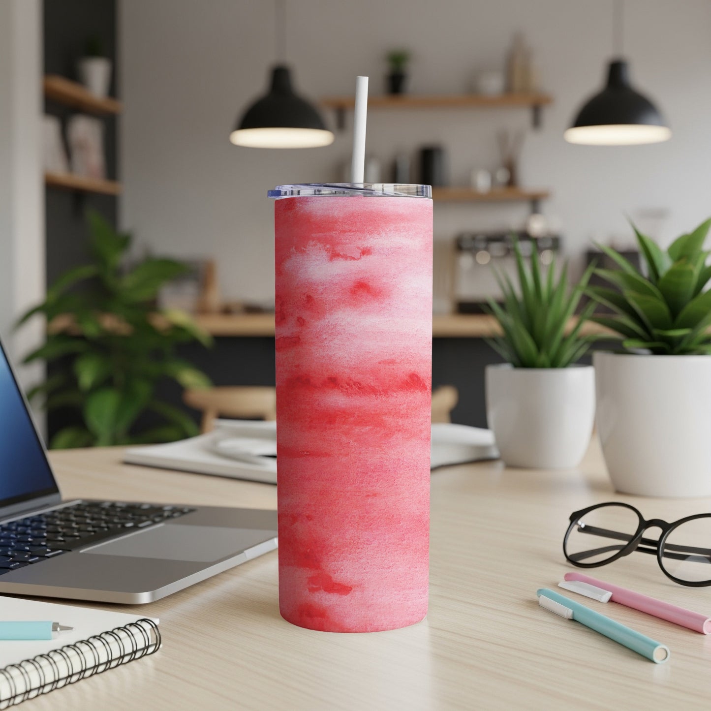 Red watercolor tumbler with white straw on a desk.