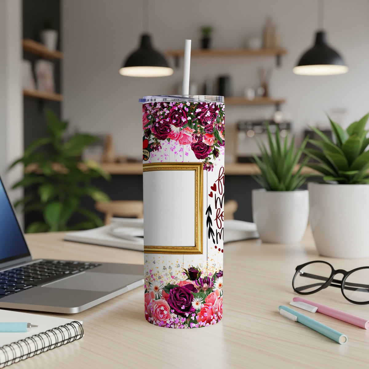 Floral patterned tumbler with a gold frame and straw on a desk.