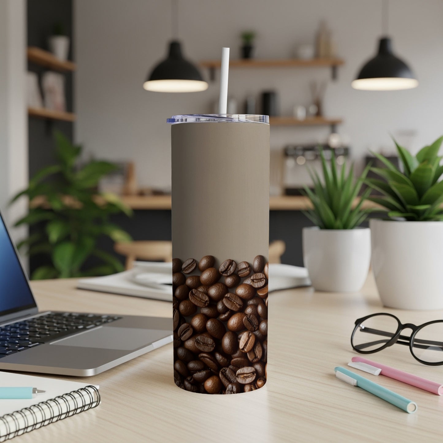 Tan tumbler with coffee beans pattern and white straw, on a desk.