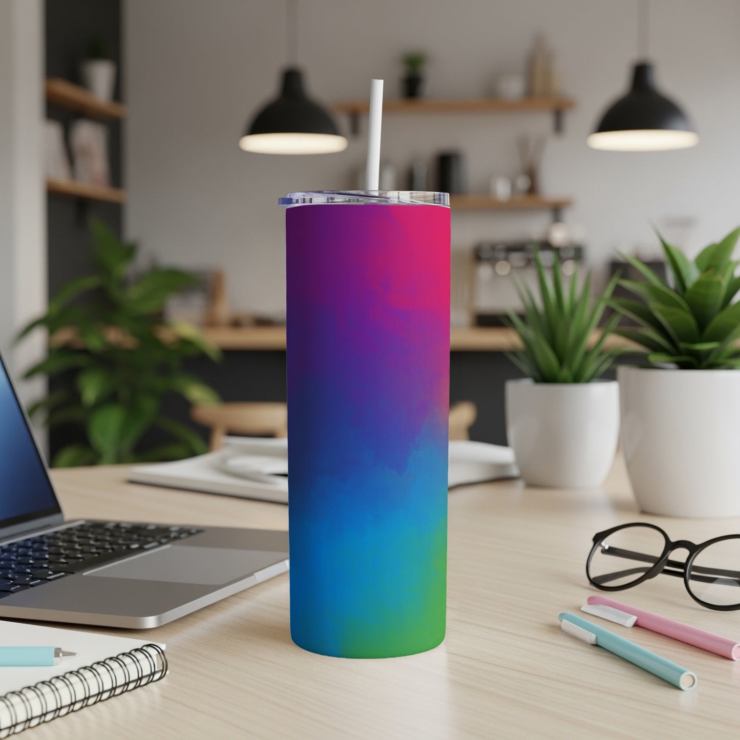 Gradient-colored tumbler with straw on a desk next to a laptop.