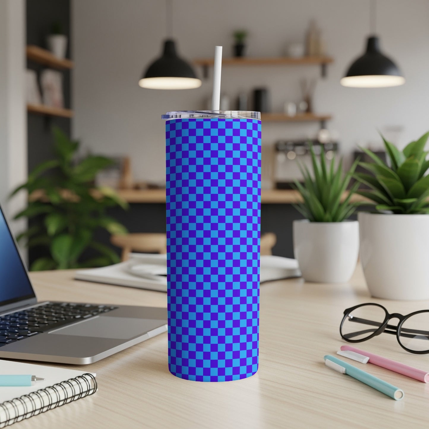 Blue and purple checkerboard tumbler with a white straw on a desk.
