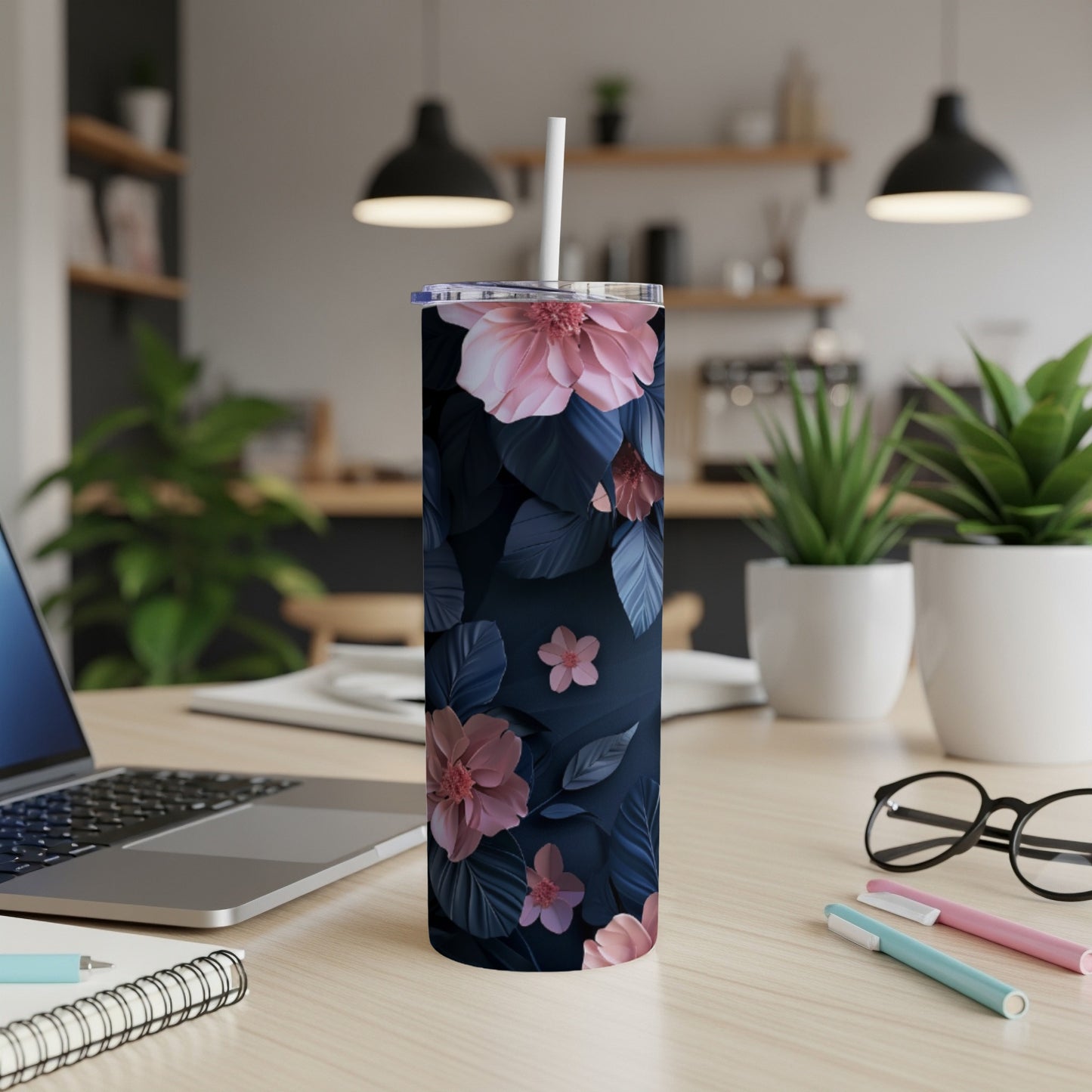 Dark floral tumbler with pink flowers and leaves, on a desk.