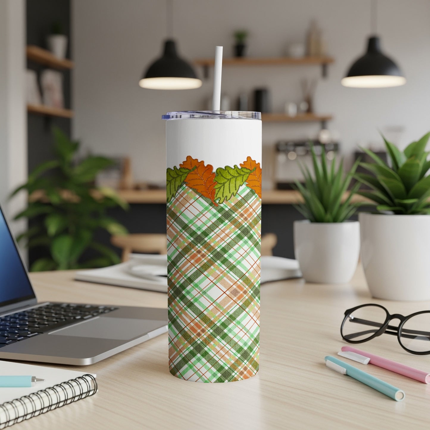 White tumbler with plaid pattern and falling autumn leaves.