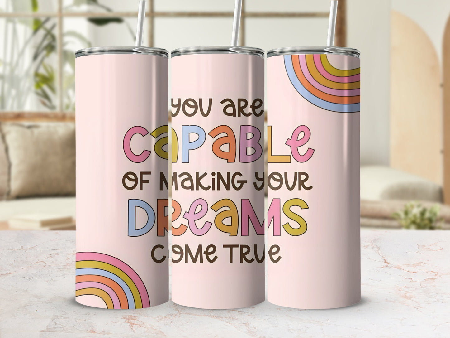 Pink tumbler with rainbow accents and "you are capable of making your dreams come true" text.