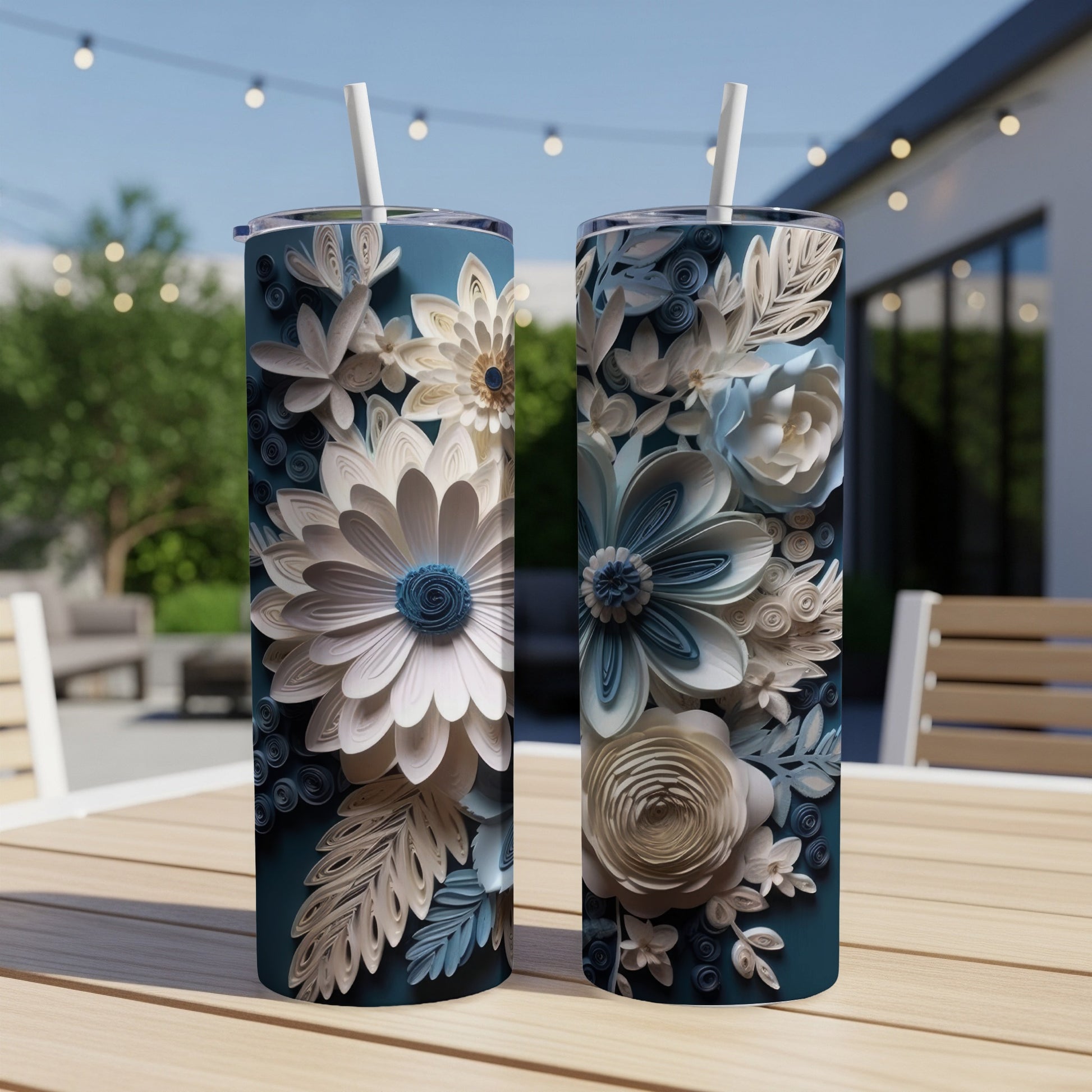 Two teal tumblers with intricate white and blue floral designs on a wooden table.