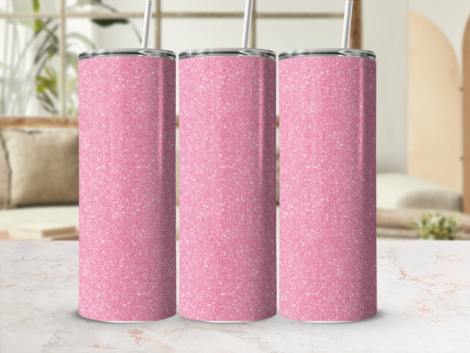 Three pink glitter tumblers with silver lids and straws sit on a marble surface.