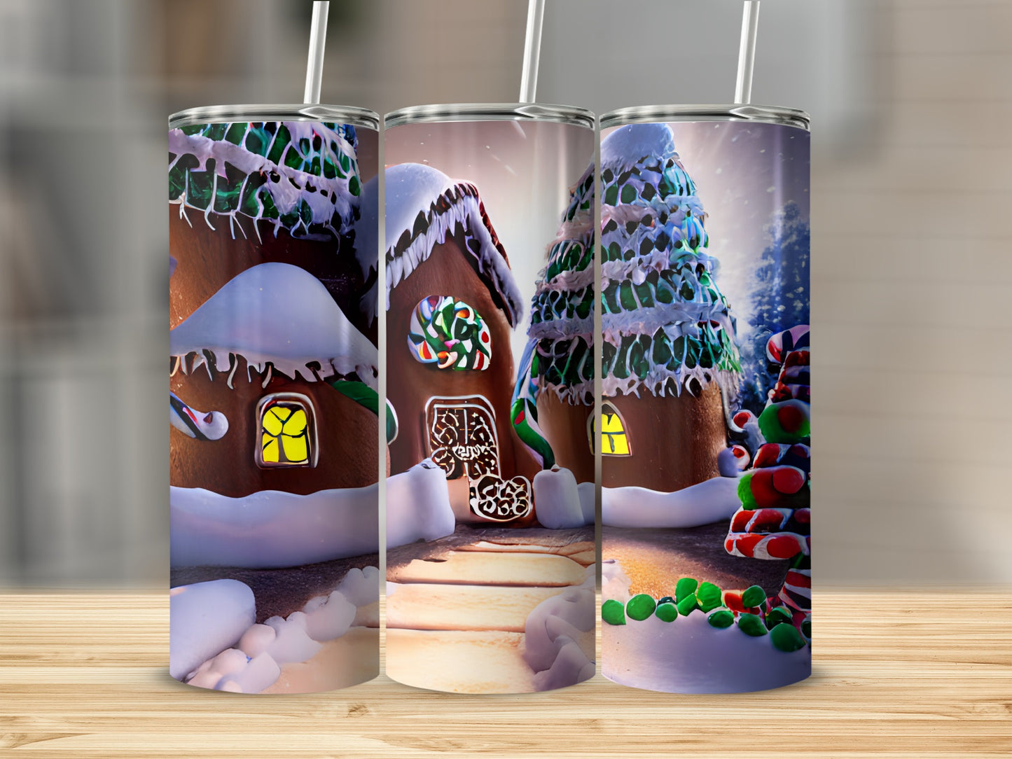 Three tumblers with gingerbread house designs, two with snow, on a wooden surface.