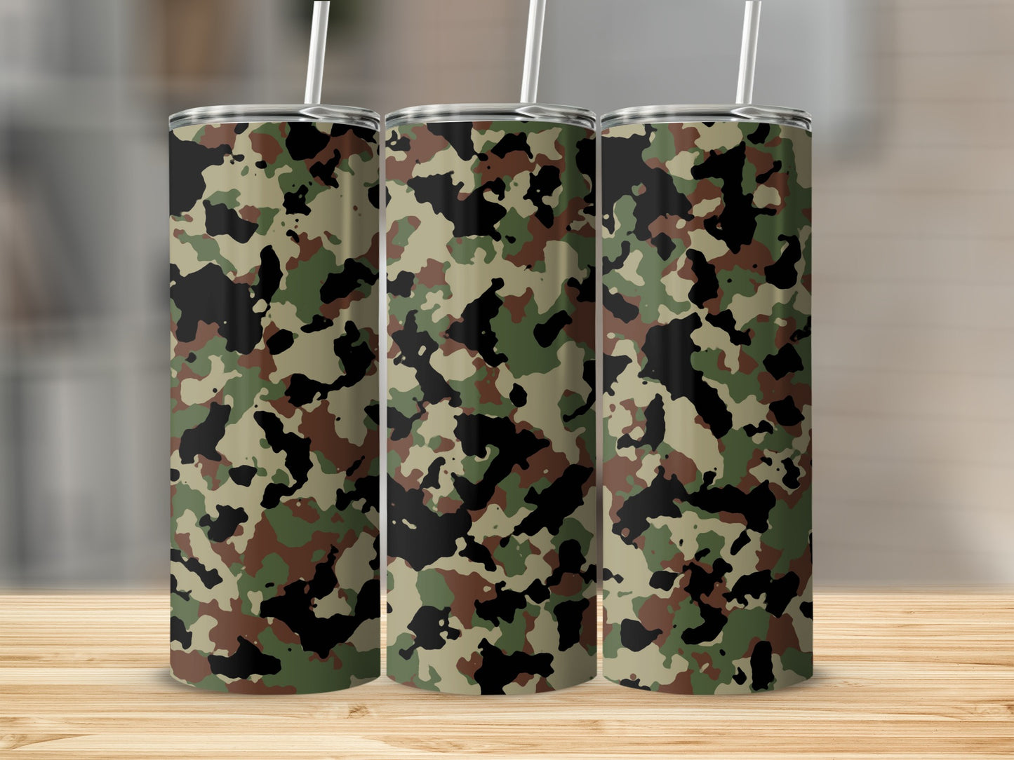 Three camouflage print tumblers with straws on a wooden surface.