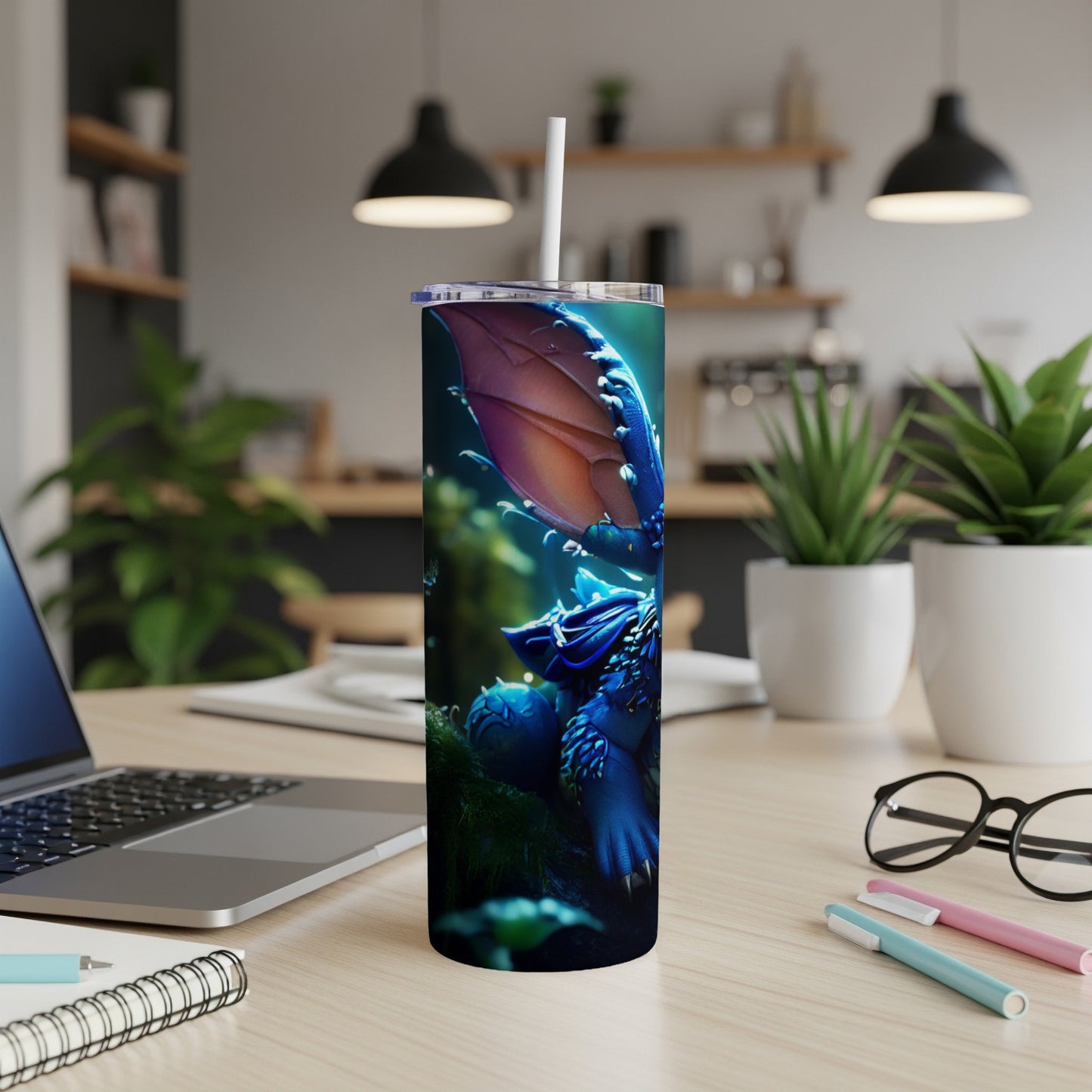 Dragon tumbler with straw on a desk with laptop and plants.