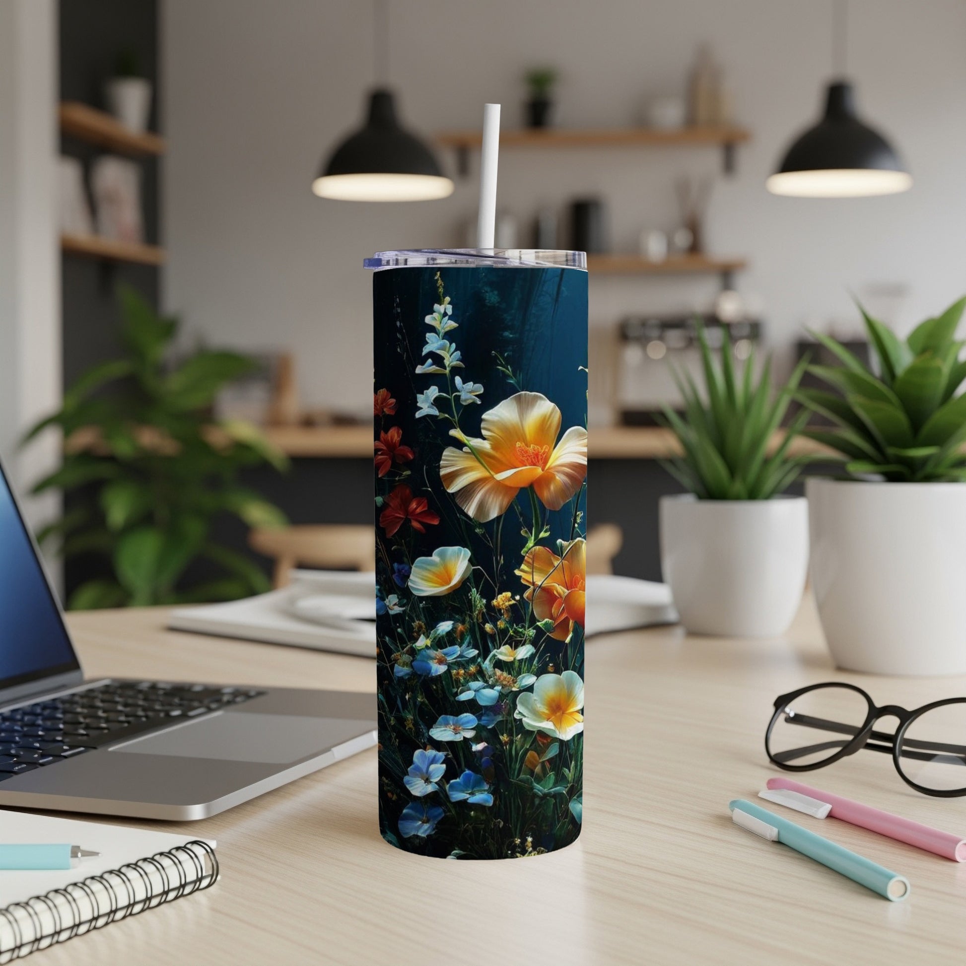 Tall tumbler with colorful floral pattern, set on a desk with a laptop and pens.