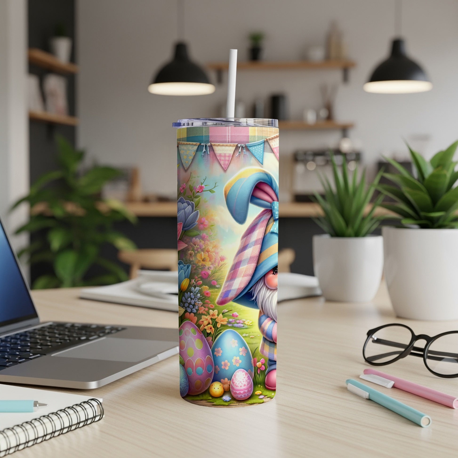 Easter gnome with decorated eggs and wildflowers on a tumbler, with a laptop and pens in the background.